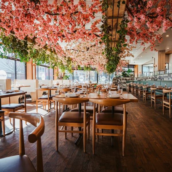 Restaurant dining room with wooden tables and chairs, adorned with pink and green floral ceiling decor.