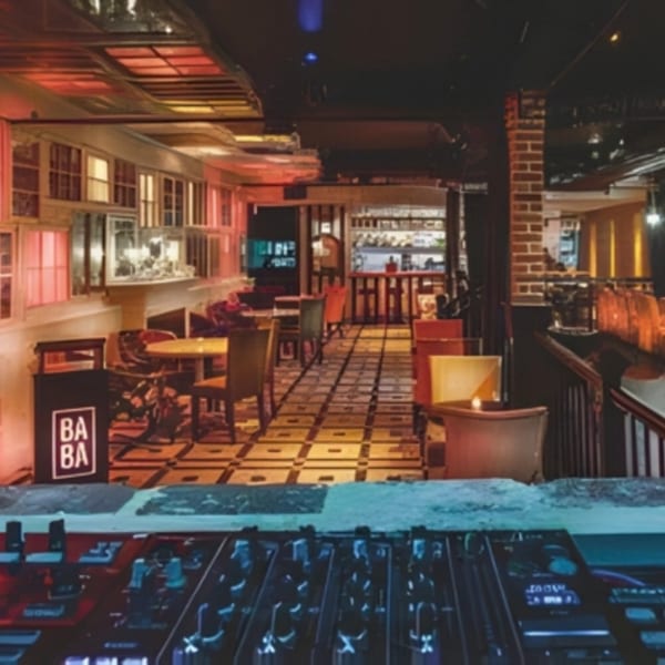 A dimly lit restaurant interior with patterned floors, brick walls, and a DJ mixer in the foreground.