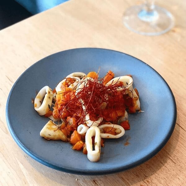 European-style calamari with diced vegetables and red chili threads on a blue plate.