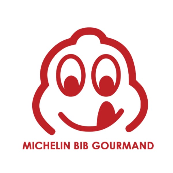 Red Michelin Bib Gourmand logo, featuring a smiling face with a tongue licking its lips.